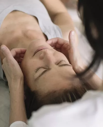 woman receiving a massage to the jaw and neck.