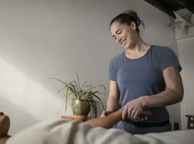 A massage therapist smiles while performing acupressure.