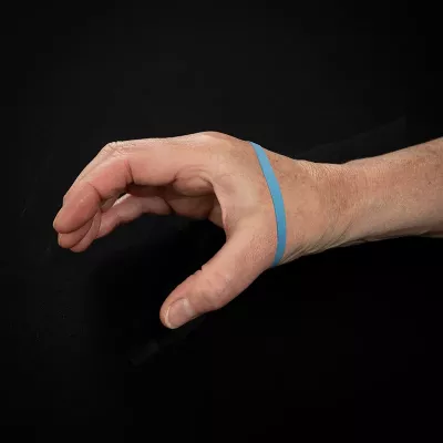 Demonstration of exercise for the thumb with rubber band around the hand and fingers, with the hand opened in a "C" shape.