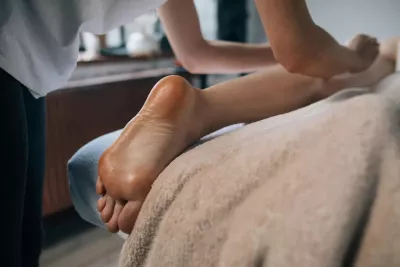 A massage therapist works on the legs of a client who is face down on a table.