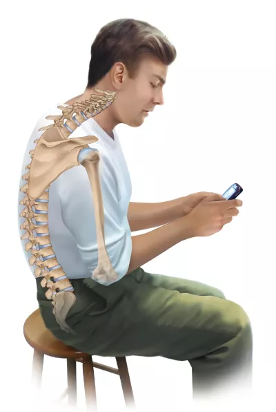 A man sits with his back curved as he looks at his phone.