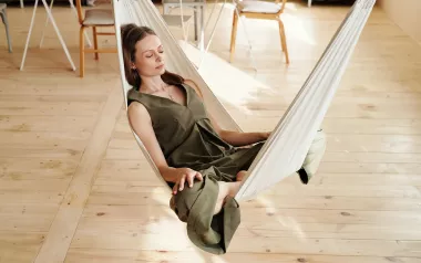 A woman sits in a hammock indoors.