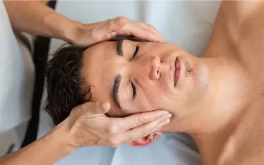 A male client receives massage therapy to the head and face.