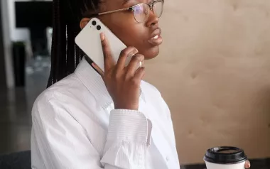 Black woman on cell phone in office setting.