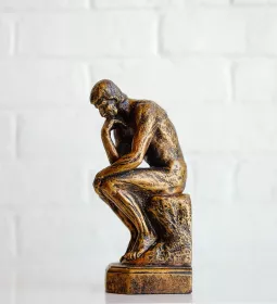 A miniature version of the statue The Thinker stands on a table