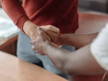 Two people shake hands, one of them using two hands.