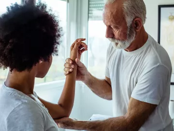 A client has their left arm examined between the wrist and the area of the upper elbow.