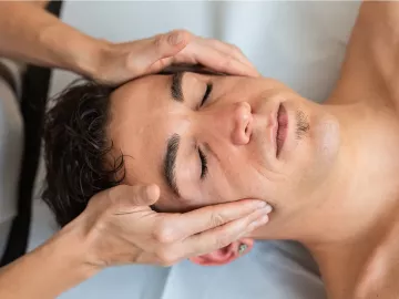 A male client receives massage therapy to the head and face.