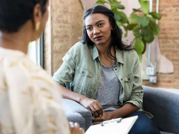 Two women, massage client and therapist, conduct a health intake.