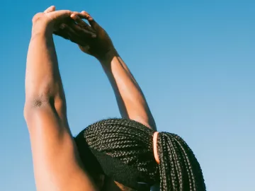 Black woman stretching arms above her head.