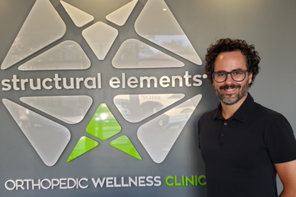 Massage therapist next to Structural Elements logo