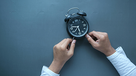 Image of an analog alarm clock against a blue background.