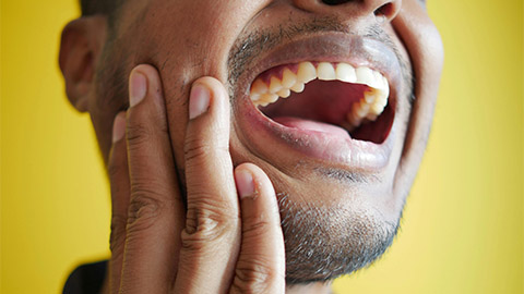 image of a person holding their jaw.