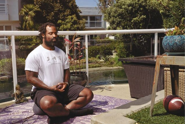 Former NFL player Ricky Williams meditates on an outdoor balcony. 
