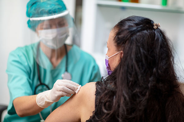 A woman receiving a vaccine injection from a health-care worker