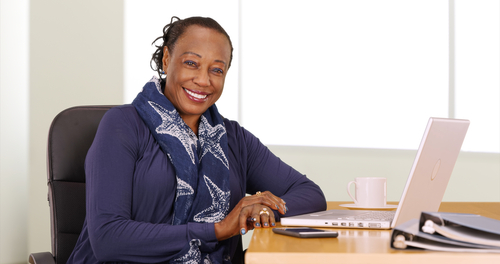African American woman sitting at a computer smiling