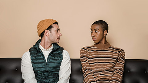 Two people sitting on a couch staring intently at each other.
