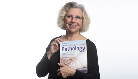 Author and educator Ruth Werner holding her book A Massage Therapistâ€™s Guide to Pathology.