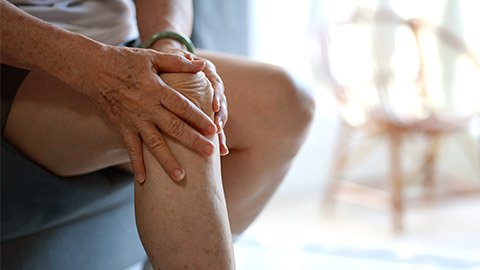 Image of an elderly man holding his right knee.