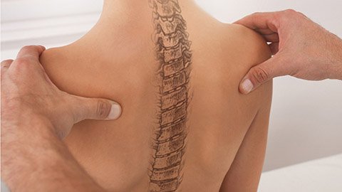 A doctor examining a woman's back with the spine drawn on the back